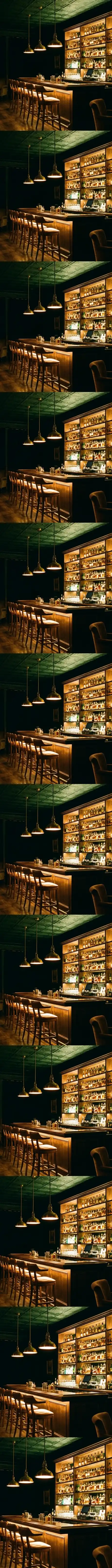 Recorrido entrando al bar: la sala en penumbra y la estanteria de botellas iluminada al fondo, que se va acercando